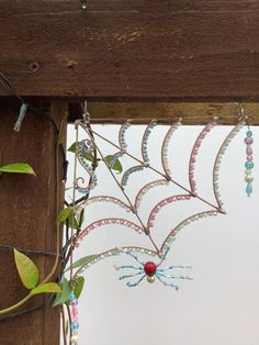 a spider web hanging from the side of a wooden structure with beads attached to it