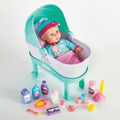 a baby doll sitting in a toy bathtub surrounded by toys and other items on a white background