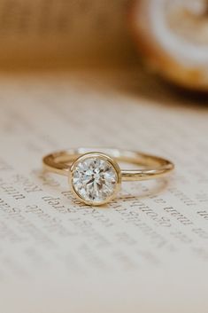 a close up view of a diamond ring on top of an open book with writing in the background