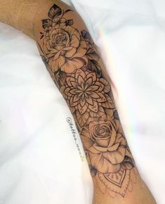 a woman's arm with flowers on it and an intricate tattoo design in the middle