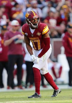 a football player is standing on the field with his hands in his pockets and looking down