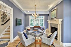 a living room filled with furniture and a fire place under a chandelier in front of a fireplace