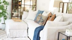 a living room filled with white furniture and lots of pillows on top of it's couch