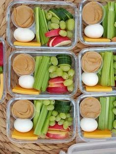 four plastic containers filled with food on top of a woven tablecloth covered flooring