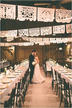 the bride and groom are kissing in front of their reception tables