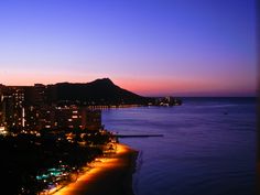 the city lights are lit up at night by the ocean