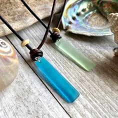 two pieces of glass sitting on top of a wooden table next to seashells