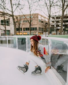 a woman sitting on top of a snow covered slope next to a skateboard ramp