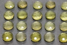 yellow glass cabochons are lined up on a gray surface with white dots in the middle