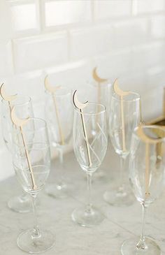 several wine glasses with wooden sticks sticking out of them on a marble countertop in front of a window