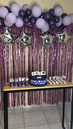 a table topped with purple and silver balloons