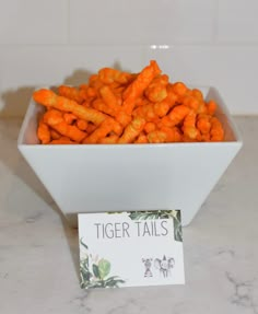 a white bowl filled with carrots next to a sign that says tiger tails on it