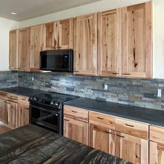 a kitchen with wooden cabinets and granite counter tops, black stove top oven and microwave