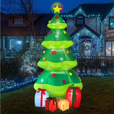 a lighted christmas tree in front of a house with presents on the ground and lights around it