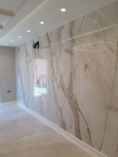 an empty room with marble walls and flooring in the middle, along with recessed lighting