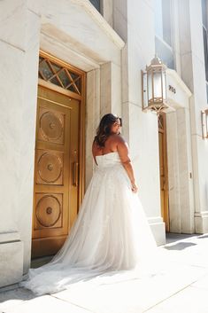 a woman standing in front of a door wearing a wedding dress