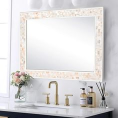 a bathroom vanity with a large mirror above it and soap bottles on the counter next to it