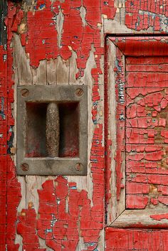 an old red painted door with a rusted metal handle on the front and side