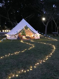 a white tent with fairy lights in the grass