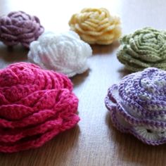 several crocheted flowers sitting on top of a wooden table