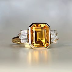 Introducing the November birth stone ring, a truly unique piece of jewelry that showcases a stunning 2.97-carat emerald-cut natural citrine center stone. This November birth stone ring is perfect for anyone born in November or for anyone who appreciates the beauty of citrine. Its bezel-set design ensures that the stone stays in a piece, while the accenting shoulders feature baguette-cut diamond set prongs to add an extra touch of elegance.  This handcrafted 18k yellow gold ring is a testament to Bling Things, Estate Diamond Jewelry, Emerald Engagement Ring Cut, Orange Sapphire, Citrine Stone, Citrine Ring, Baguette Cut Diamond, 18k Yellow Gold Ring, Engagement Ring Cuts