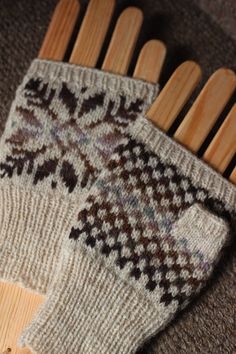 two wooden combs sitting next to each other on a carpeted floor in front of a pair of mittens