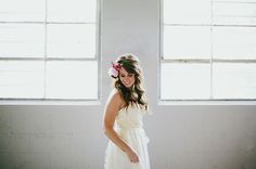 a woman in a white dress standing next to a window with flowers in her hair