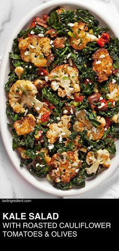 kale salad with roasted cauliflower, tomatoes and olives in a white bowl