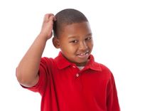 a young boy in a red polo shirt holding his hair up to the side with one hand