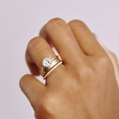 a woman's hand with a diamond ring on top of her finger and an engagement band