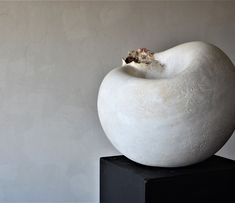 a large white sculpture sitting on top of a black block in front of a wall