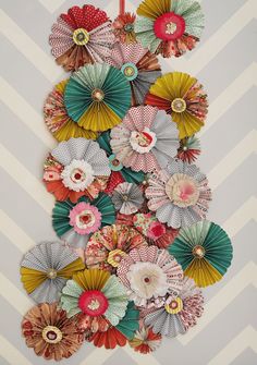 colorful paper flowers are hanging on the wall