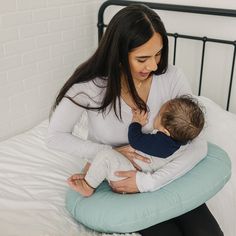 a woman holding a baby on top of a bed