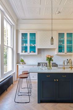 a kitchen with white and blue cabinets, wood flooring and an island in the middle