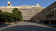 people are walking down the street in front of some large buildings with windows and balconies