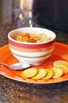 a bowl filled with pasta and crackers on top of an orange plate