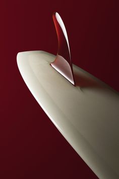 a red and white surfboard with a curved tail sticking out of it's side