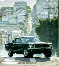 an old muscle car driving down the road