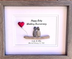 two rocks sitting on top of a wooden frame with a red balloon in the middle