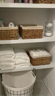 the shelves in this bathroom are organized with baskets, towels and other items for storage