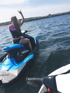 a woman riding on the back of a blue and black sea - doon boat