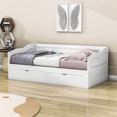 a white bed with two drawers underneath it in a room next to a table and chair