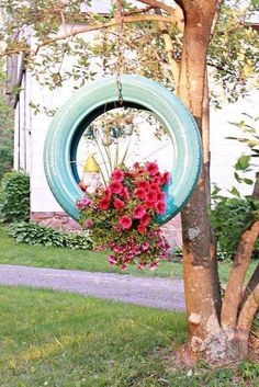 a blue tire hanging from a tree with flowers in the center and on it's side