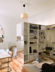 a living room filled with furniture next to a white table and book shelf on top of a hard wood floor