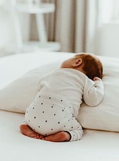 a baby laying on top of a white pillow