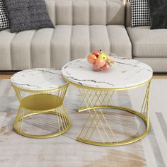 two tables sitting on top of a white rug in front of a couch with pillows