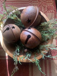 three wooden balls with faces painted on them in a bowl filled with grass and branches