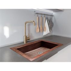 a kitchen sink with wooden utensils hanging on the wall