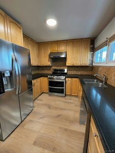 an empty kitchen with stainless steel appliances and wood cabinets