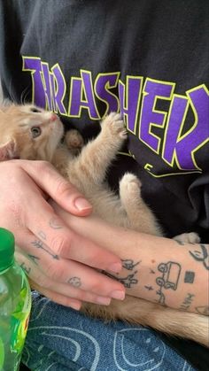 a person holding a small dog with tattoos on their arms and arm, in front of the camera